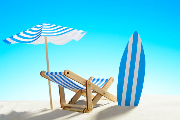 istock Deck chair under an umbrella and a surfboard on sandy beach 932206260