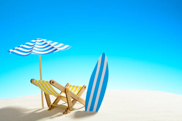 istock Deck chair under an umbrella and a surfboard on sandy beach 932206282