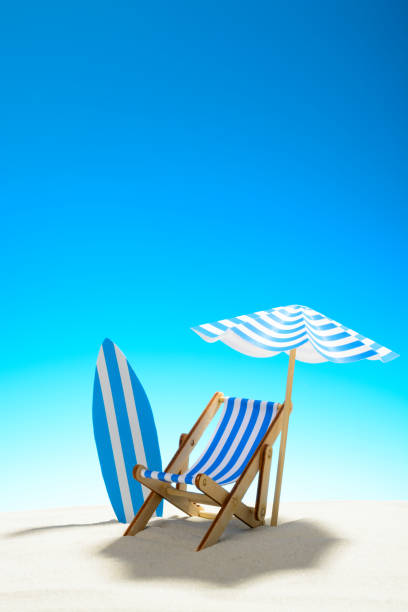 istock Deck chair under an umbrella and a surfboard on sandy beach 932206286