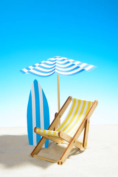 istock Deck chair under an umbrella and a surfboard on sandy beach 932206288