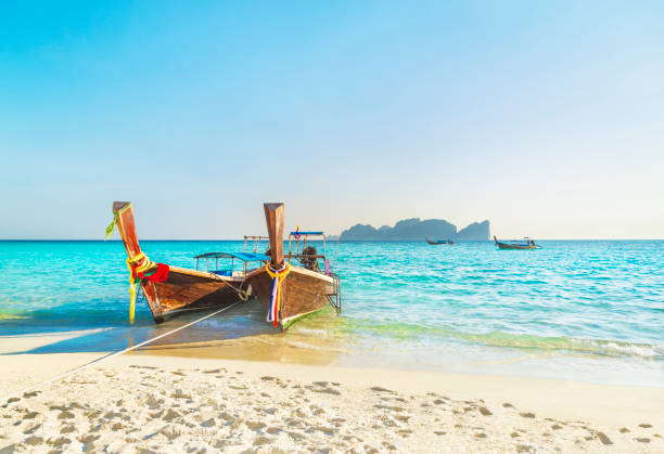 two traditional thai longtail boats at famous sunset long beach, thailand, koh phi phi don island, krabi province, andaman sea - phi imagens e fotografias de stock