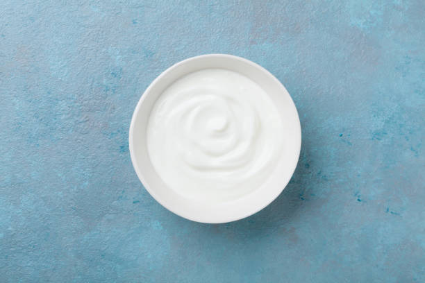 istock Greek yogurt in bowl on blue stone table top view. 932232022