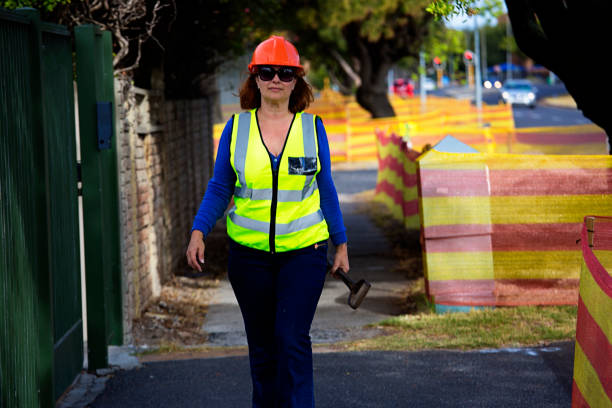 istock Woman construction worker walks along a sidewalk 932236098
