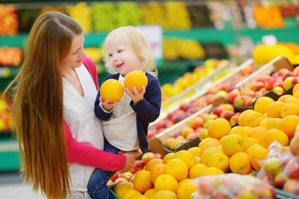 istock Mother and daughter choosing an orange in a store 932237786