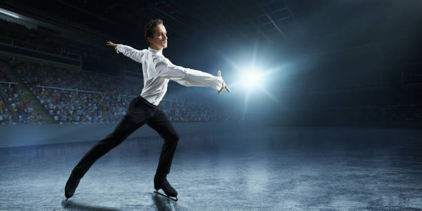 Figure skating. Male Ice skater Figure skating. Male ice skater performs a complicated trick on the professorial ice rink. Young man stand on the ice in the rays of light. figure skating stock pictures, royalty-free photos & images