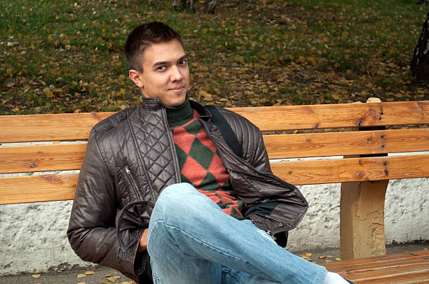 istock Young man sitting on a bench in autumn park 93224214