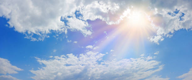 Miraculous Heavenly Light Panorama Banner Wide blue sky, fluffy clouds and a beautiful warm orange yellow sun beaming down radiating depicting a holy entity miracle stock pictures, royalty-free photos & images