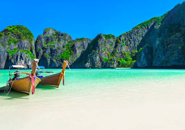Maya Bay beach with two longtail boats, Ko Phi Phi Leh Island, Thailand Famous scenic Maya Bay beach at Ko Phi Phi Leh Island with two traditional longtail taxi boats mooring and steep limestone hills in background, Thailand, part of Krabi Province, Andaman Sea krabi province stock pictures, royalty-free photos & images