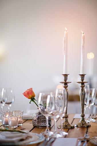 Two Candles on a table with a rose at a Wedding Reception with champagne glasses and plates with a white background Stellenbosch Cape Winelands South Africa