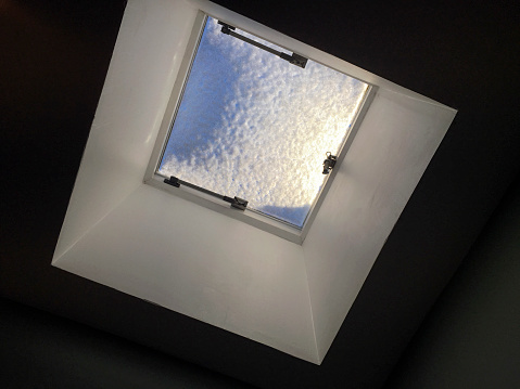 Ceiling window with snow, blue sky and sunshine. Taken on a mobile device.