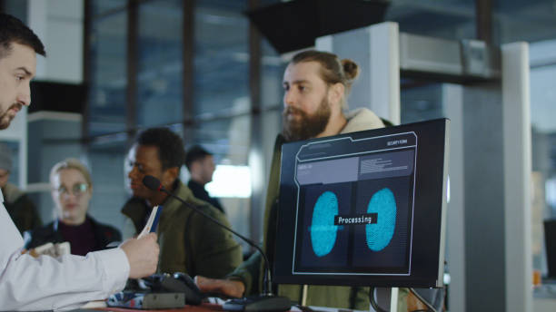 Man passing biometric control at counter Man giving fingerprints with sensor when passing special control point in airport with employee watching at screen. biometric security stock pictures, royalty-free photos & images