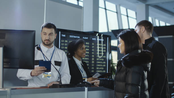Airport workers checking documents at control point Diverse employees of airport checking passports and biometric data working with passengers. airport check in counter photos stock pictures, royalty-free photos & images