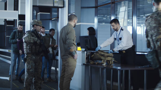 Airport security apprehending a suspect Airport security apprehending a suspect or passenger with men in military uniform pointing a weapon at a kneeling man with his hands on his head at the check-in gate for departures. jeff goulden border security stock pictures, royalty-free photos & images