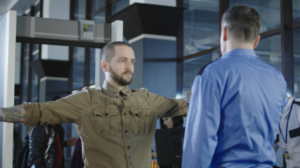 istock Airport worker checking passenger with metal detector 932264196
