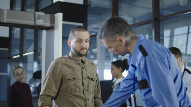 istock Airport worker checking passenger with metal detector 932264212