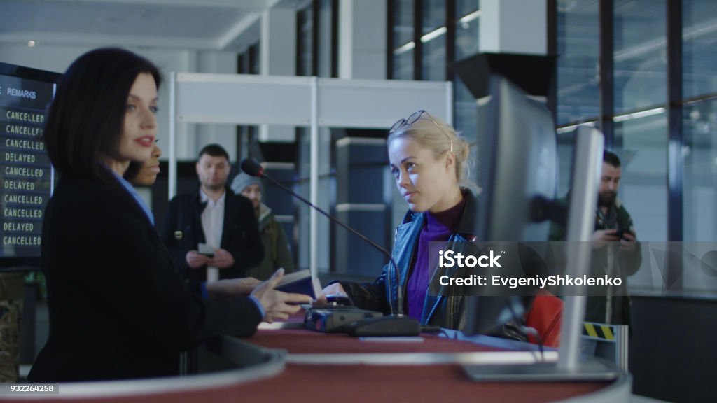 Airport security personnel processing passengers Airport security personnel processing passengers at a check-in counter in a departures or arrivals hall checking their identity against passports and thumb prints Checkout Stock Photo