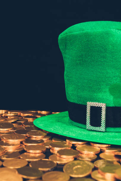 istock green hat on shining golden coins isolated on black, st patricks day concept 932264570
