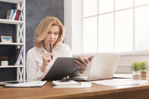 istock Thoughtful businesswoman reading document at office desktop 932264822