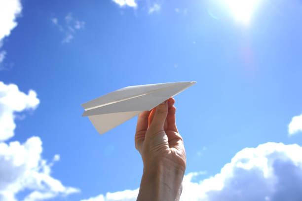 istock Hand with paper plane on a background of clouds 932271786