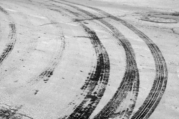 istock Wet tyre tracks on dirty asphalt road. 932272404