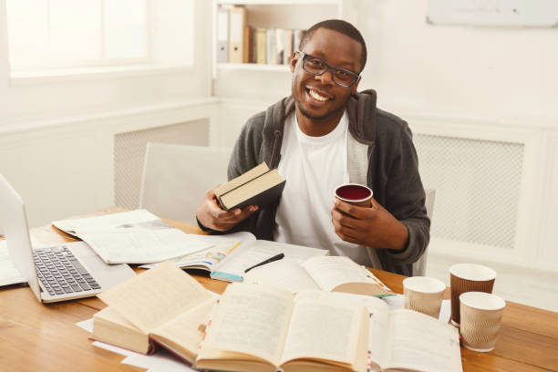 istock Happy black male student studying at table full of books 932272510