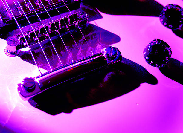 Electric Guitar Pink Tones Close-up of an electric guitar. Colors digitally altered. Pink and purple tones, volume and base nobs, steel stringed guitar taken with natural light. pink guitar stock pictures, royalty-free photos & images