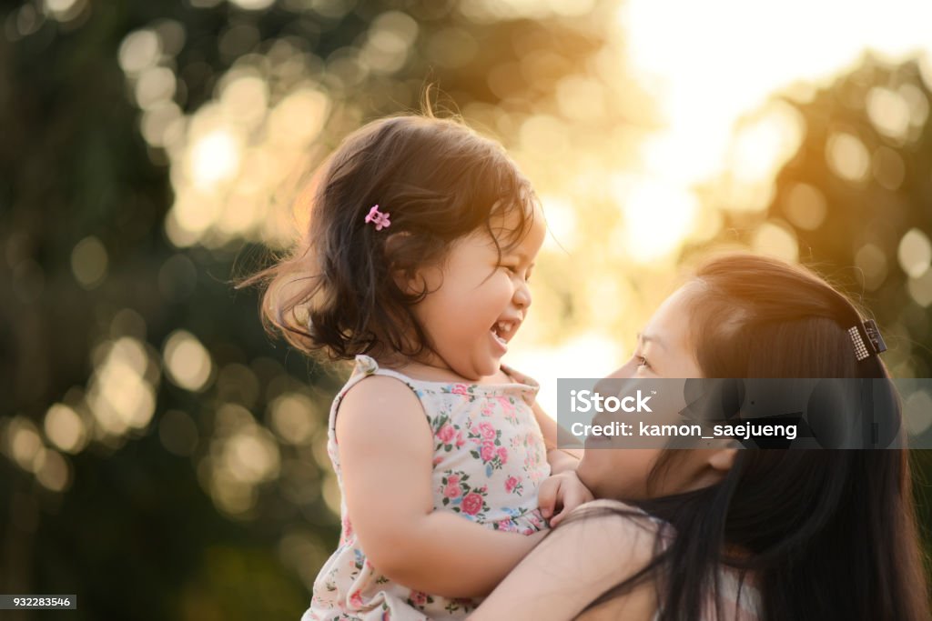 Sweet Beautiful baby girl with hug of mother and playing. Happy loving family kissing and hugging. Mother Stock Photo