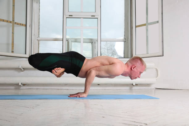 istock Sporty man practicing yoga. Mayurasana, peacock pose 932284638