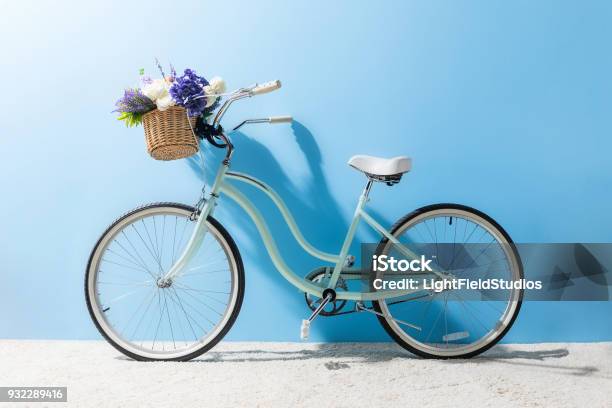 Side View Of Bicycle With Flowers In Basket In Front Of Blue Wall Stock Photo - Download Image Now