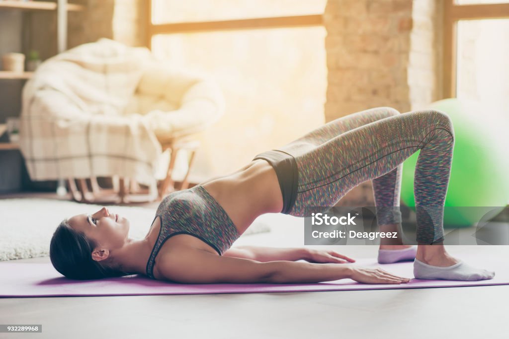 Ich will attraktiv und sportlich sein! Fröhliches anmutiges starke energetische dauerhaftes sexy muskulöses Mädchen in engen modischen Outfit ist zu bauen Muskeln auf Klasse Übungen - Lizenzfrei Frauen Stock-Foto