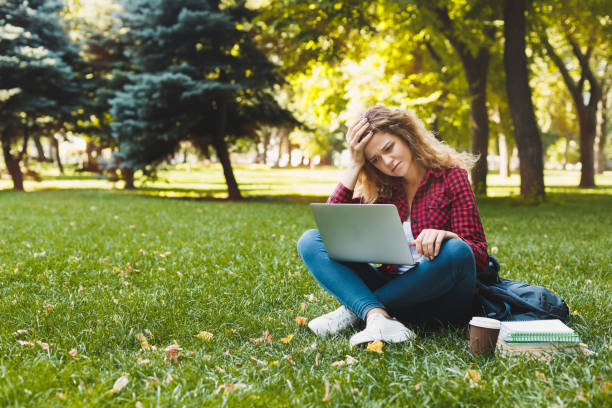istock Desparate young woman using a laptop outdoors 932290286