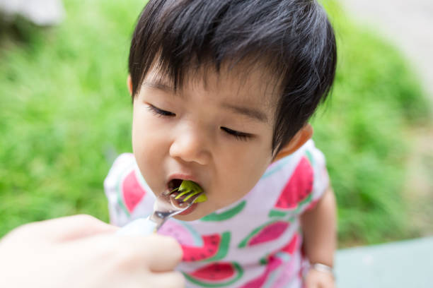 istock Mother feeding baby to eat fruit 932292746