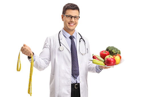 Doctor with a measuring tape and a plate with vegetables and fruit isolated on white background