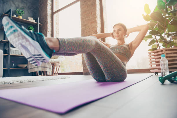 ângulos foto de esportiva muito forte muscular flexível mulher atraente fazer abdominais e mantendo as pernas no ar, tentando manter o equilíbrio em reflexão, brilho do sol, raio, raio, dia ensolarado - sit ups - fotografias e filmes do acervo