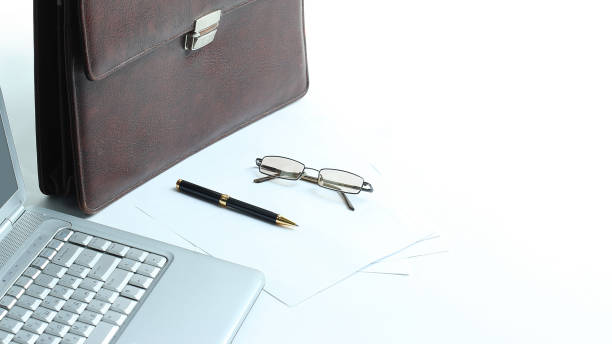 istock open laptop , briefcase and pen on the desktop 932298544