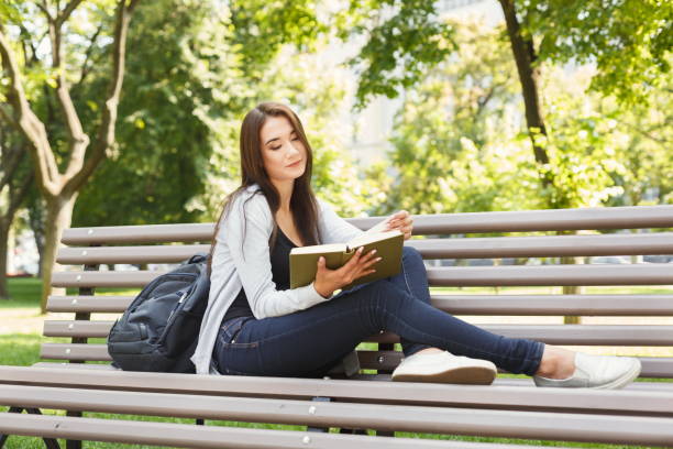 istock Young woman reading book in park copy space 932299778
