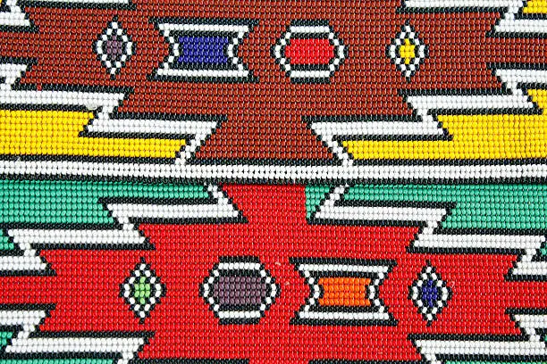 Ndebele beadwork detail: from South Africa that I bought from illegal immigrants from Malawi in 2008 at a curio market near Hartebeespoort Dam, one hour from Johannesburg. This pattern is called after the Ndebele tribe that paint these blocks and triangles on their huts as ritual from folklore. The design is not unique or original, has no. copyright, it is a mere replica of a pattern used by the Ndebele tribe. The men from Malawi know that this colourful pattern sell well to tourist, they make a few and then take the money back to their home country. This design is popular and used very often as a background for African Safari logos or in a light box and has no copyright.