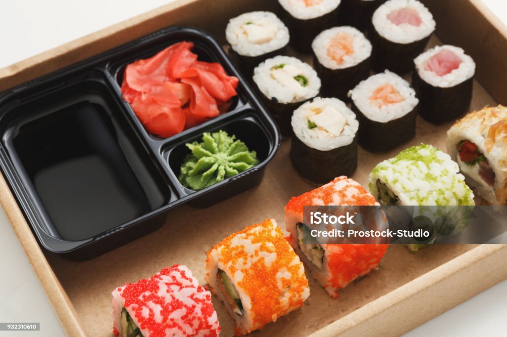 Closeup of set of sushi maki and rolls Japanese restaurant, sushi rolls in wooden platter on white background. Set for one person, with ginger, soy sauce and wasabi. Closeup, copy space Backgrounds Stock Photo