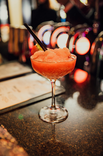 A frozen strawberry daiquiri sitting on a bar.