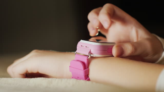 Close-up of a child's hand with a pink smart watch