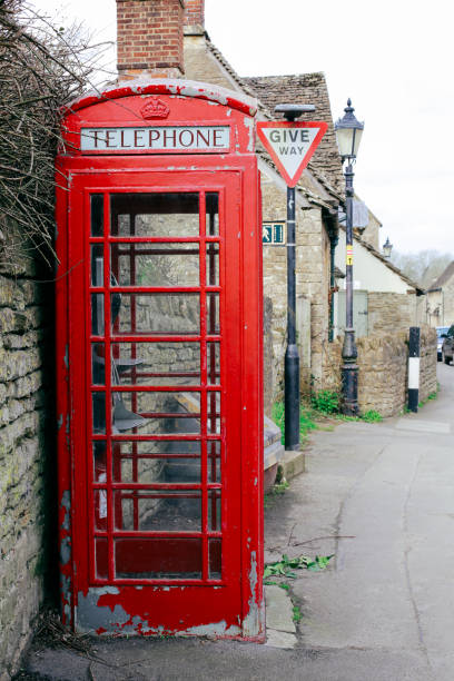 istock Old red telephone box in a small English Village. 932314400