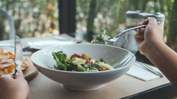 istock A hand using fork to scoop up Ceasar salad to eat with pizza on dining table in the restaurant 932314454
