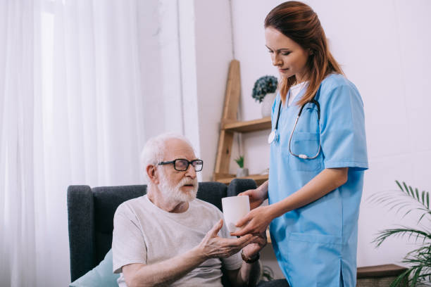 istock Nurse helping senior patient to hold a cup 932317728