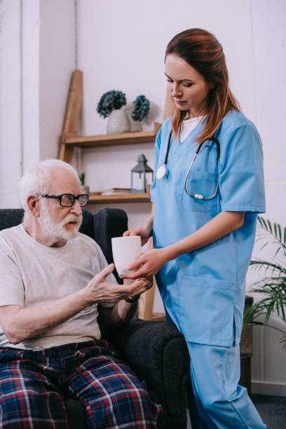 istock Nurse giving cup with drink to senior patient 932318614