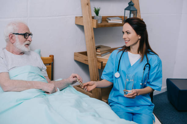 istock Senior patient in bed taking medications from female nurse 932318988