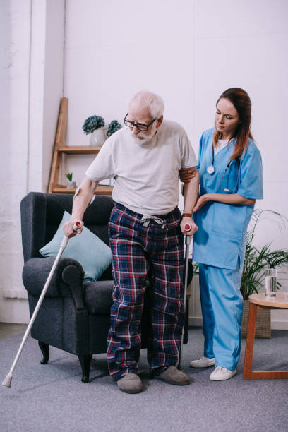 istock Nurse supporting male patient with crutches 932319530