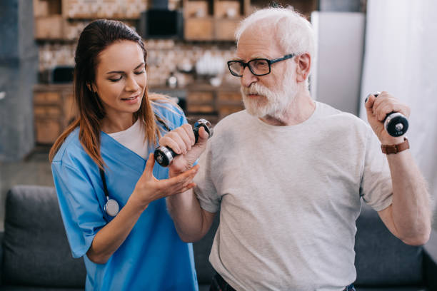 istock Nurse assisting senior man exercising with dumbbells 932321928