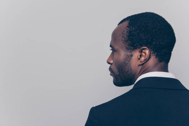 istock Rear view with half turned head, close up portrait with copy space, empty place for advertisement of confident, attractive, concentrated manager, guy in tux, isolated on grey background 932322730