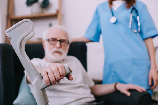 istock Nurse standing behind senior man with crutch 932325934