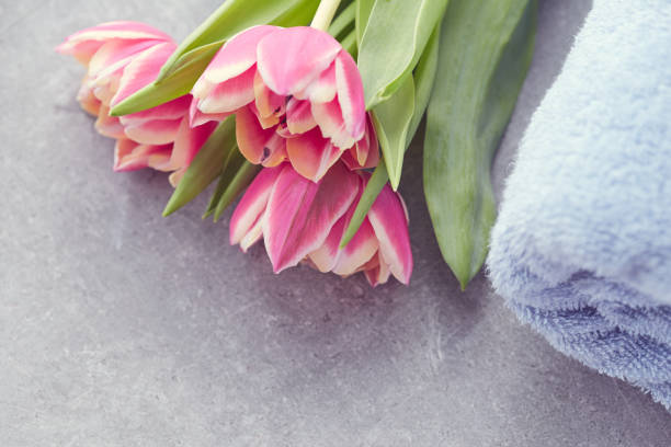 istock Spa concept with grey towel and tulip flowers on grey background. Top view 932326194